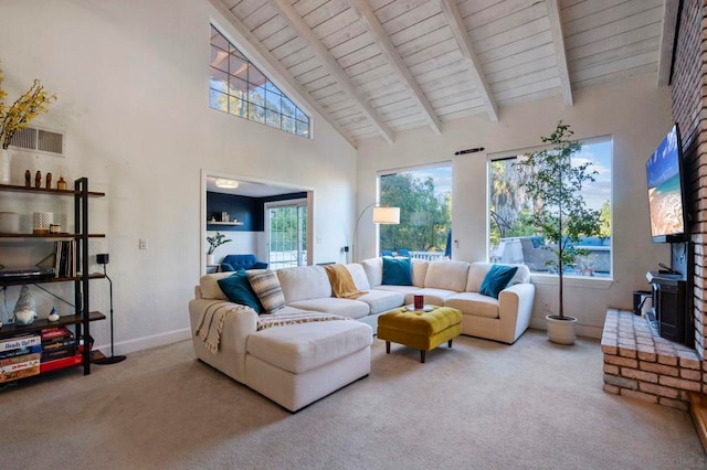 living room with beam ceiling, a healthy amount of sunlight, carpet floors, and a wood stove