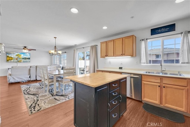 kitchen with dishwasher, hanging light fixtures, a kitchen island, ceiling fan with notable chandelier, and sink