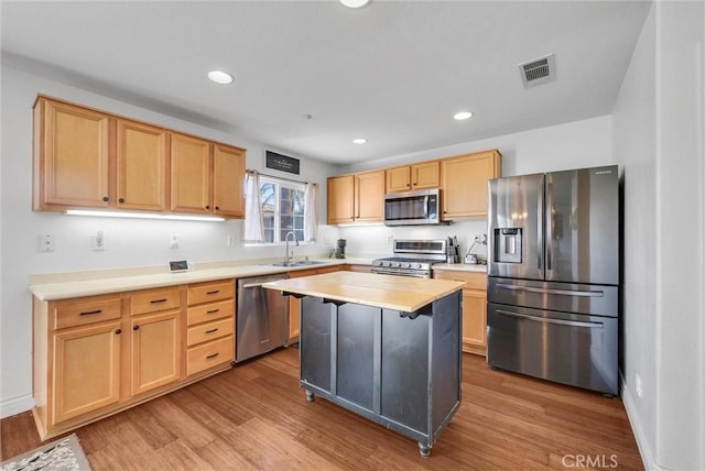 kitchen featuring light hardwood / wood-style floors, stainless steel appliances, a center island, light brown cabinetry, and sink