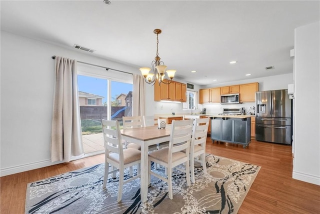 dining room featuring a notable chandelier, light hardwood / wood-style floors, and plenty of natural light