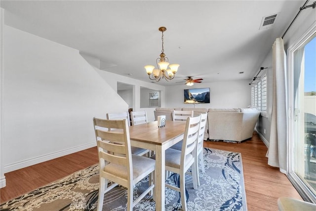 dining room with ceiling fan with notable chandelier and light hardwood / wood-style floors