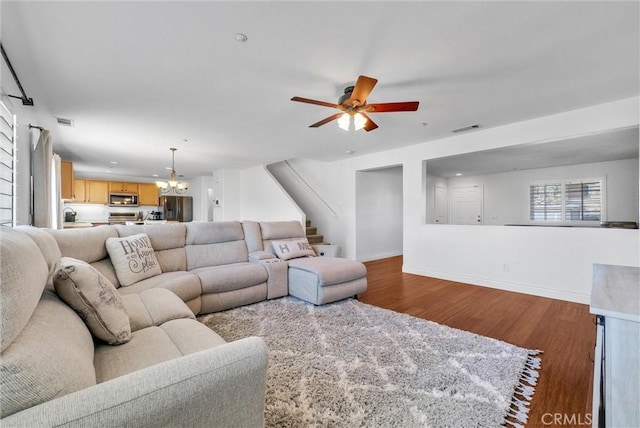 living room featuring ceiling fan with notable chandelier and wood-type flooring