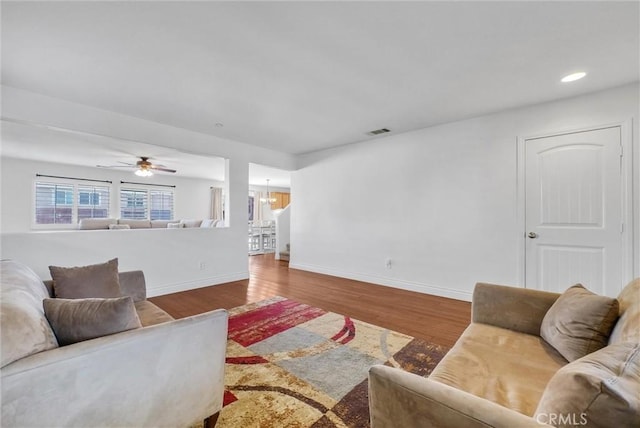 living room with ceiling fan with notable chandelier and hardwood / wood-style floors