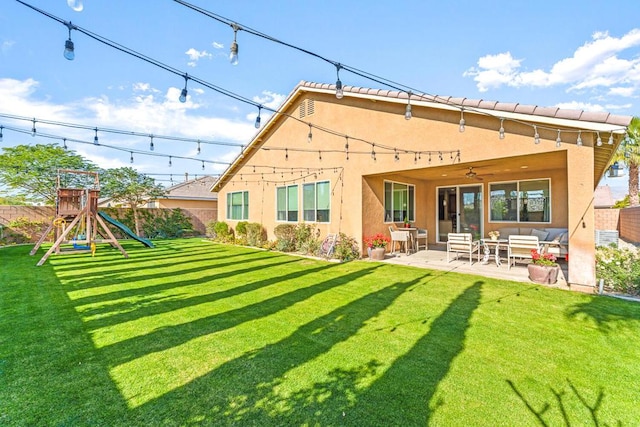 rear view of house featuring ceiling fan, a lawn, a playground, and a patio area