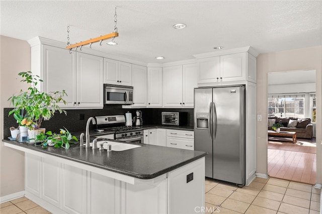 kitchen with stainless steel appliances, white cabinets, light tile patterned flooring, decorative backsplash, and kitchen peninsula