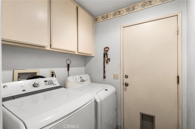 clothes washing area with cabinets and washing machine and clothes dryer