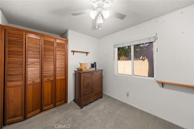 carpeted bedroom with a textured ceiling, a closet, and ceiling fan