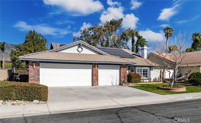 ranch-style home featuring a garage and solar panels