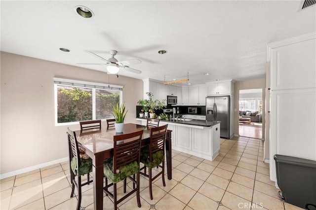 tiled dining area with plenty of natural light and ceiling fan