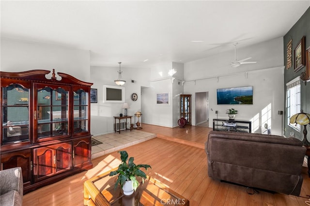 living room with hardwood / wood-style flooring, ceiling fan, and high vaulted ceiling