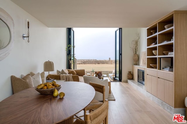 dining room with floor to ceiling windows, a fireplace, and light hardwood / wood-style flooring