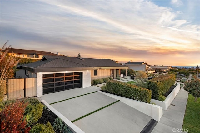 modern home featuring an attached garage, a patio area, fence, and concrete driveway