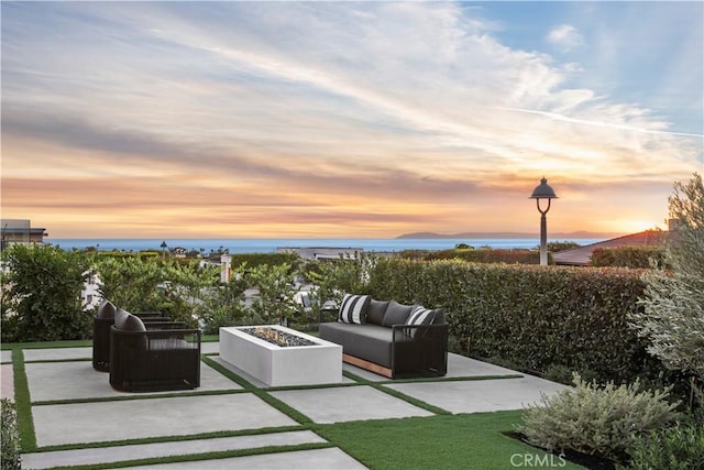 patio terrace at dusk featuring an outdoor living space with a fire pit and a water view