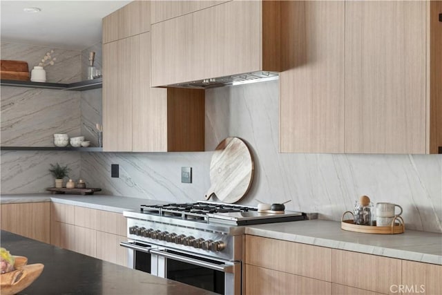 kitchen with backsplash, light stone countertops, range with two ovens, and light brown cabinets