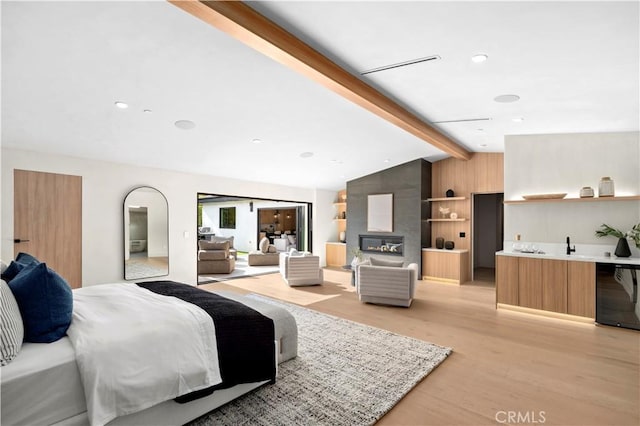 bedroom featuring wet bar, vaulted ceiling with beams, and light wood-type flooring