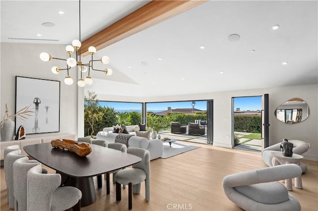 dining area featuring lofted ceiling with beams, an inviting chandelier, and light hardwood / wood-style flooring