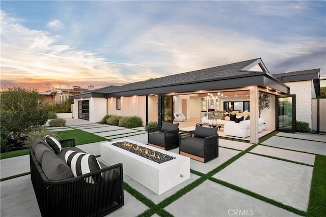 back of property featuring a patio and an outdoor living space with a fire pit