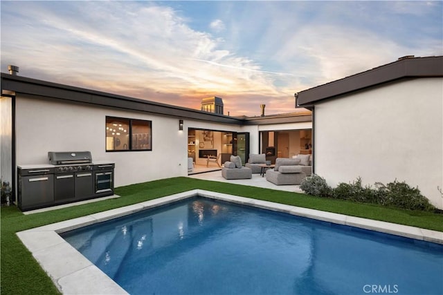 back house at dusk featuring area for grilling, outdoor lounge area, a yard, and a patio area