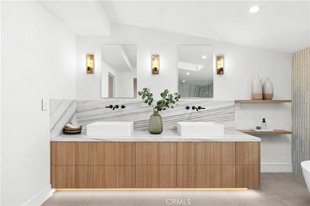 bathroom with vanity, a tub to relax in, and vaulted ceiling