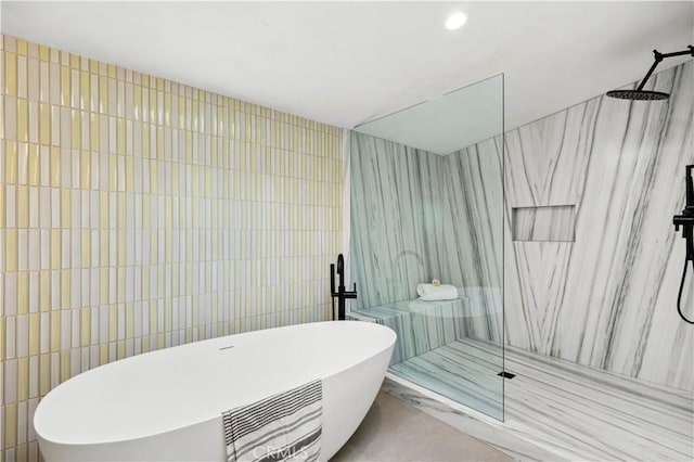 bathroom featuring tile patterned floors, tile walls, a marble finish shower, and a freestanding bath