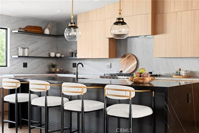 kitchen featuring light brown cabinetry, sink, a kitchen bar, decorative backsplash, and hanging light fixtures