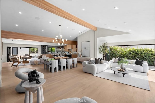 living room with lofted ceiling with beams, an inviting chandelier, and light wood-type flooring