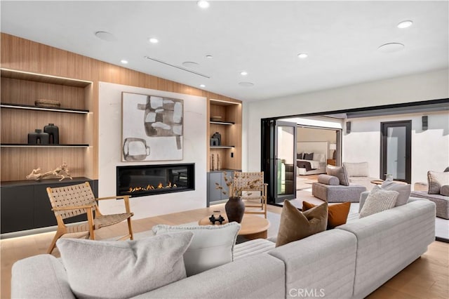 living room featuring light hardwood / wood-style flooring, wooden walls, and built in shelves