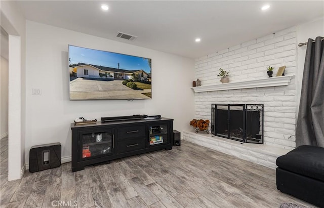 living room featuring a brick fireplace and hardwood / wood-style floors