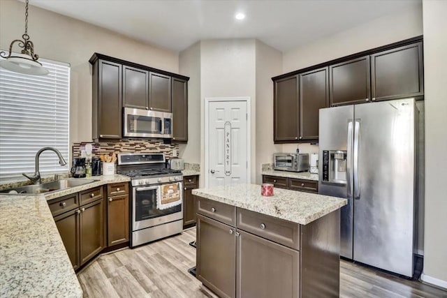 kitchen with sink, dark brown cabinets, hanging light fixtures, light hardwood / wood-style flooring, and appliances with stainless steel finishes