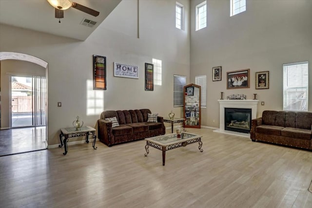 living room featuring a high ceiling, ceiling fan, and light hardwood / wood-style floors