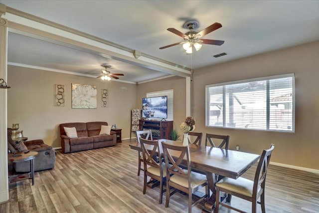 dining area featuring ornamental molding, a fireplace, ceiling fan, and light hardwood / wood-style flooring