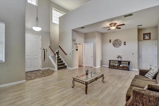 living room featuring a towering ceiling, ceiling fan, and light hardwood / wood-style flooring