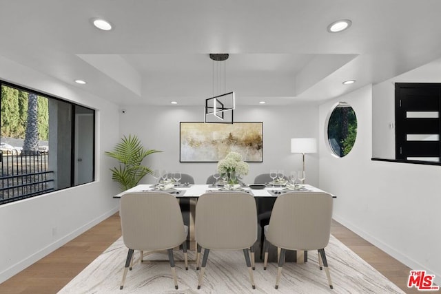 dining room with a raised ceiling and light wood-type flooring