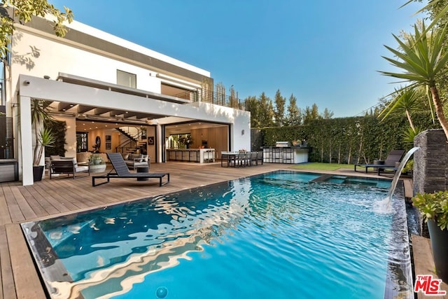 view of pool featuring exterior bar and a deck