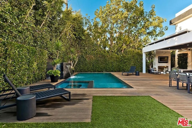 view of swimming pool with pool water feature, an outdoor fireplace, and a deck