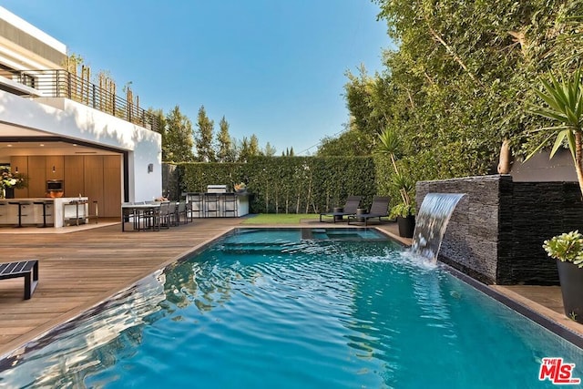 view of swimming pool with a wooden deck, an outdoor bar, and pool water feature