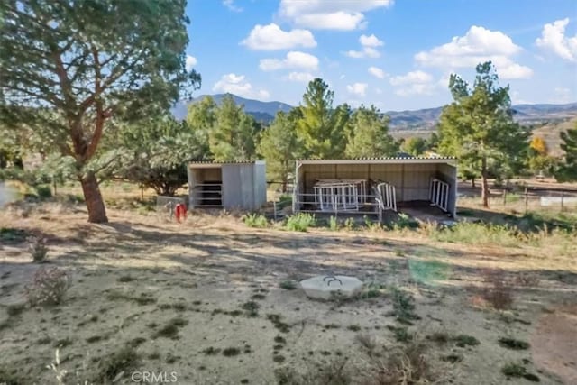 back of property with a rural view, a mountain view, and an outdoor structure