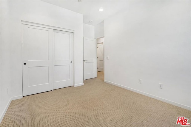 unfurnished bedroom featuring light colored carpet and a closet