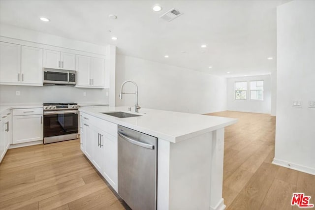 kitchen featuring stainless steel appliances, a center island with sink, white cabinets, and sink