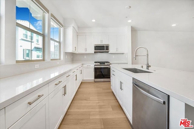 kitchen featuring sink, white cabinetry, light wood-type flooring, and appliances with stainless steel finishes