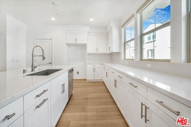 kitchen with white cabinets, dishwasher, light hardwood / wood-style floors, and sink