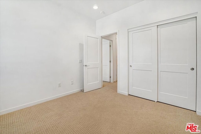 unfurnished bedroom with a closet and light carpet