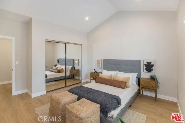 bedroom featuring lofted ceiling, light hardwood / wood-style floors, and a closet