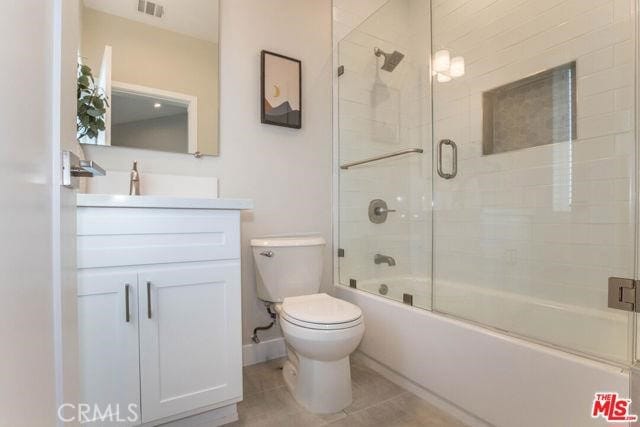 full bathroom with bath / shower combo with glass door, vanity, tile patterned floors, and toilet