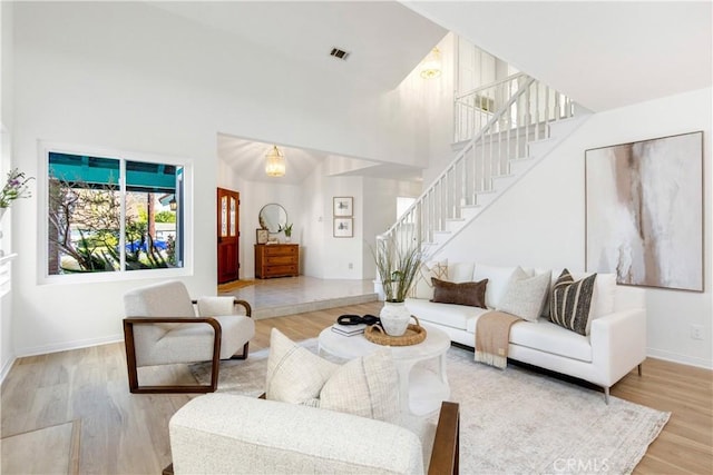 living room featuring a towering ceiling and light hardwood / wood-style flooring