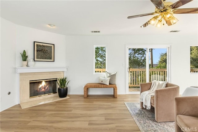 sitting room with ceiling fan, light hardwood / wood-style flooring, and a high end fireplace