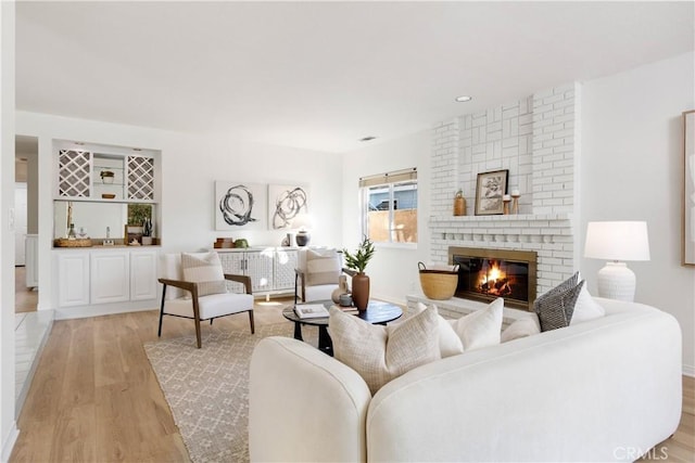 living room featuring light hardwood / wood-style floors and a brick fireplace