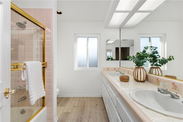 full bathroom with hardwood / wood-style floors, toilet, combined bath / shower with glass door, and vanity