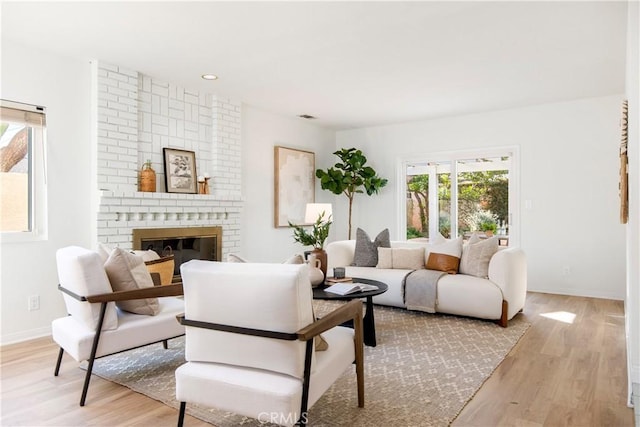 living room featuring light hardwood / wood-style flooring and a brick fireplace