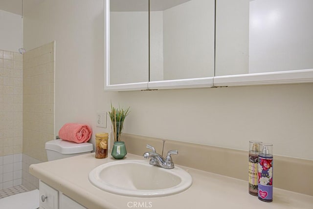 bathroom featuring toilet, vanity, and a tile shower